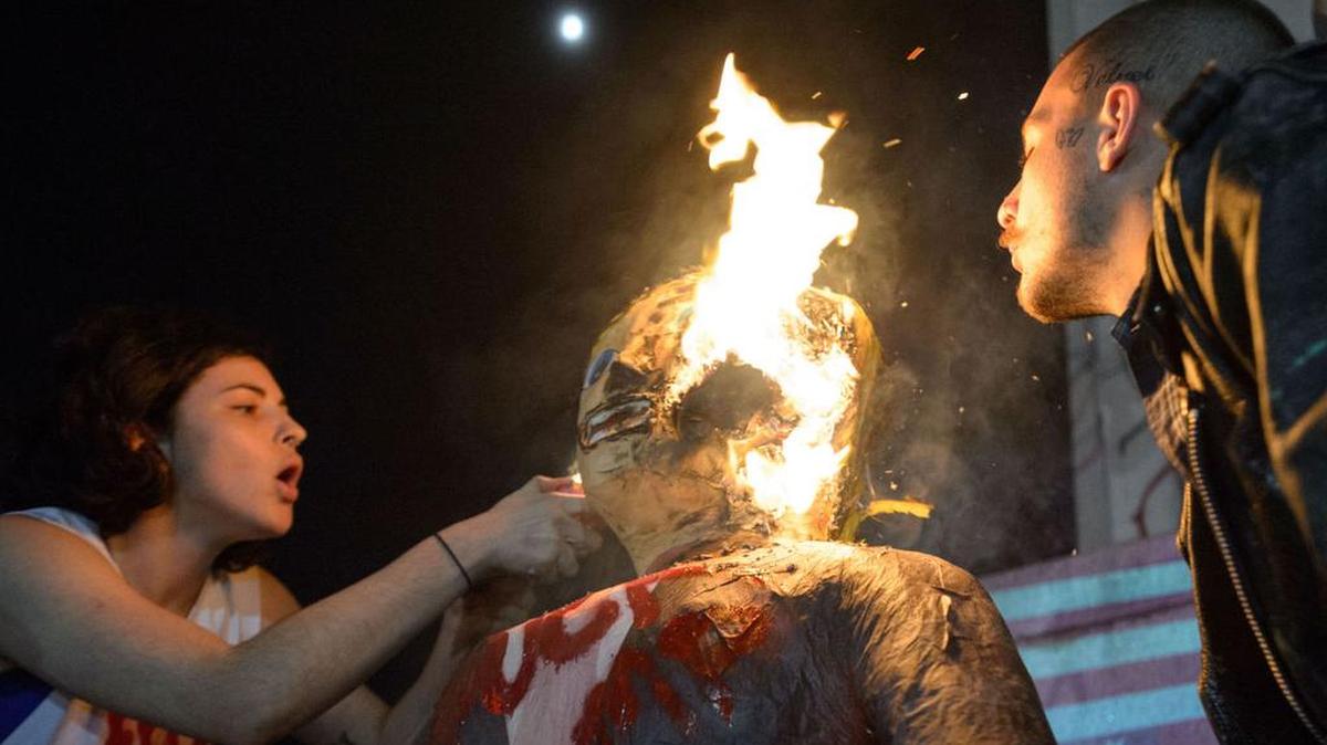 A man named Blue Velvet, right, sets fire to an effigy of Donald Trump, next to a woman who gave the name J. Stroh at Lee circle during an anti-Trump protest in New Orleans on Wednesday, Nov. 9, 2016.