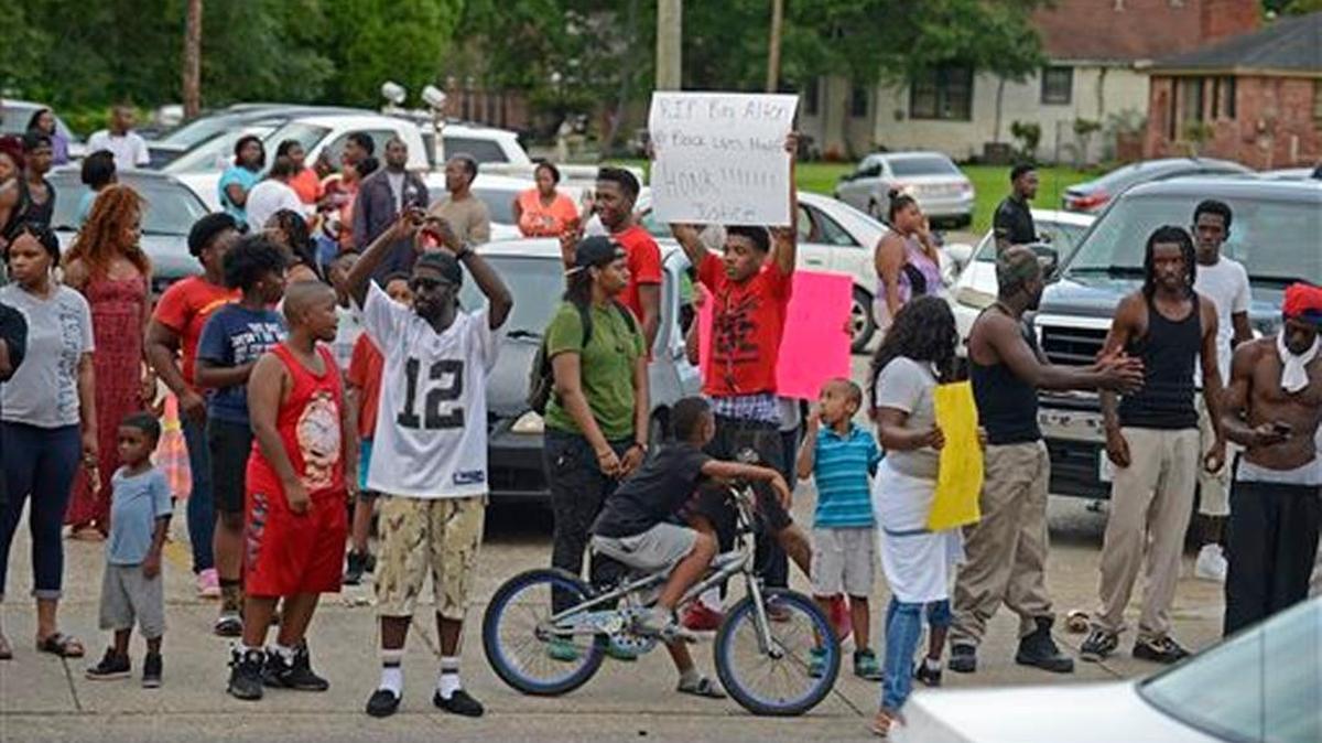 People gather in protest outside of the Triple S Food Mart on N. Foster at Fairfields Avenue, after the officer-involved fatal shooting of Alton Sterling on Tuesday, July 5, 2016, in Baton Rouge, La. An autopsy shows Sterling, 37, of Baton Rouge, died Tuesday of multiple gunshot wounds to the chest and back, said East Baton Rouge Parish Coroner Dr. William Clark. Officers responded to the store about 12:35 a.m. Tuesday after an anonymous caller indicated a man selling music CDs and wearing a red shirt threatened him with a gun, said Cpl. L'Jean McKneely. (Hilary Scheinuk/The Advocate via AP)