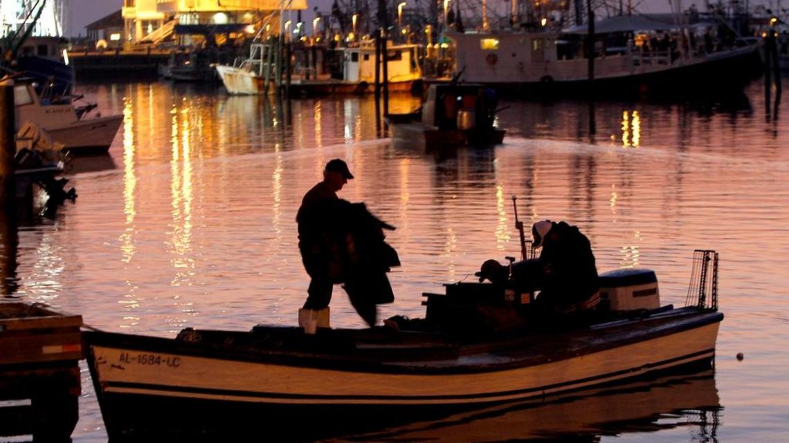 Crewmen carry oyster bags to the boat Friday morning at dawn at the Pass Christian harbor.