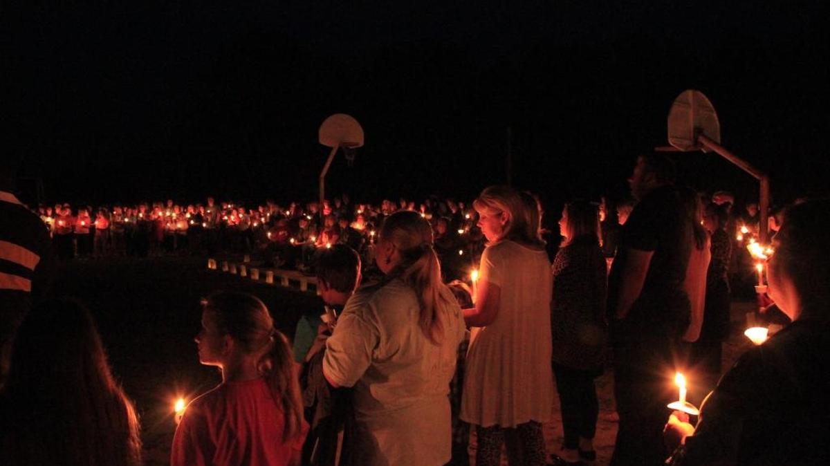 Nearly a thousand people hold candles during a vigil remembering three siblings killed in a crash Saturday in George County.