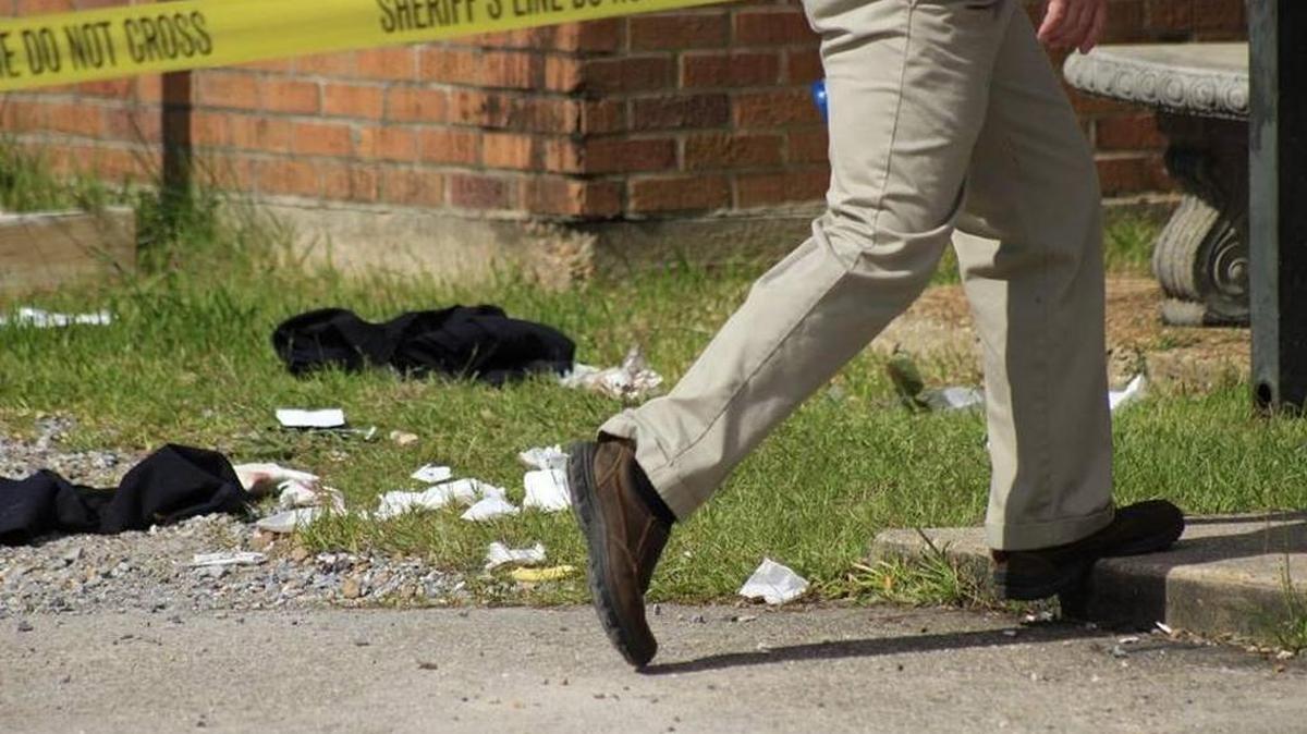 An investigator walks past Chief Mike De Nardo’s personal belongings scattered behind the Bay St. Louis police station after De Nardo shot himself to death on Sept. 8, 2016.