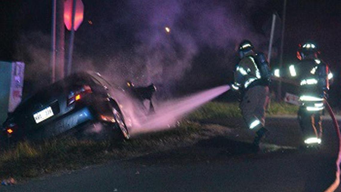 Two Bay St. Louis firefighters extinguish a burning car on Tuesday evening. Moments before, two Bay St. Louis police officers broke out a window of the vehicle and pulled a man to safety.