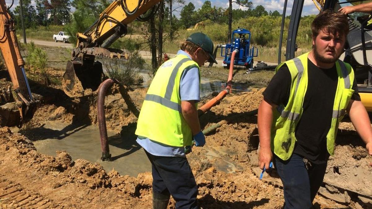 Tyler Allen, right, and Gabriel Armstrong of Utility Partners work Tuesday to contain raw sewage until repairs can be completed to a 24-inch pressurized line that broke on Glascock Drive in Harrison County's industrial park off Cowan-Lorraine Road.