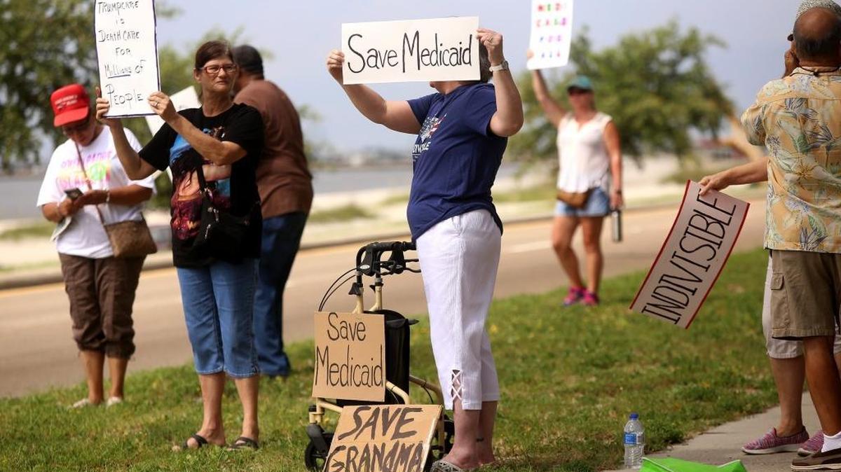 Community members gather in front of USM Gulf Park Campus in Long Beach on Saturday to protest the U.S. Senate's proposed changes to our nation's health care.