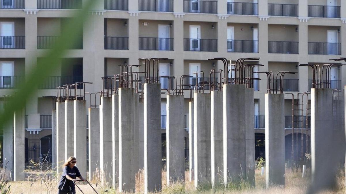 The caretaker for property formerly known as Village at Henderson Point cuts the grass there on Wednesday. Harrison County ordered the unfinished structures be demolished in 2016 after residents of the Inn by the Sea condominiums, background, complained about the unfinished project.