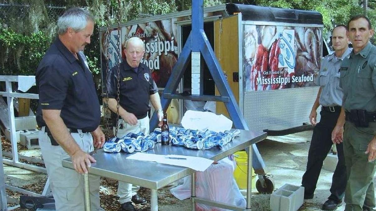 Officers from the Mississippi departments of Marine Resources, left, and Wildlife, Fisheries and Parks, are examining beer cans and a bottle retrieved from the boat of Donald Bernius, who killled one D’Iberville man and permanently injured another while boating drunk in 2009 of the Tchoutacabouffa River. Bernius, also from D'Iberville, is serving 20 years in state prison for causing a death while driving drunk.