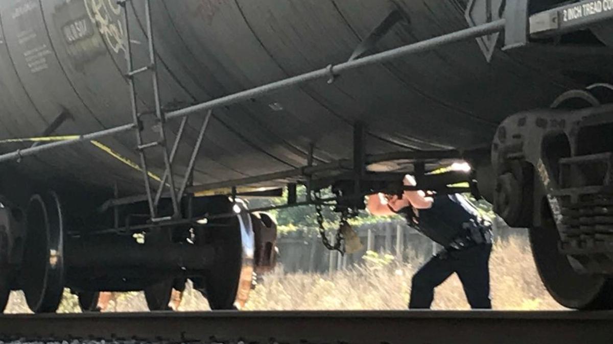 A Biloxi police officer looks under the carriage of a freight train that struck and killed a Biloxi woman near Edgewater Mall on Thursday, Oct. 12, 2017.