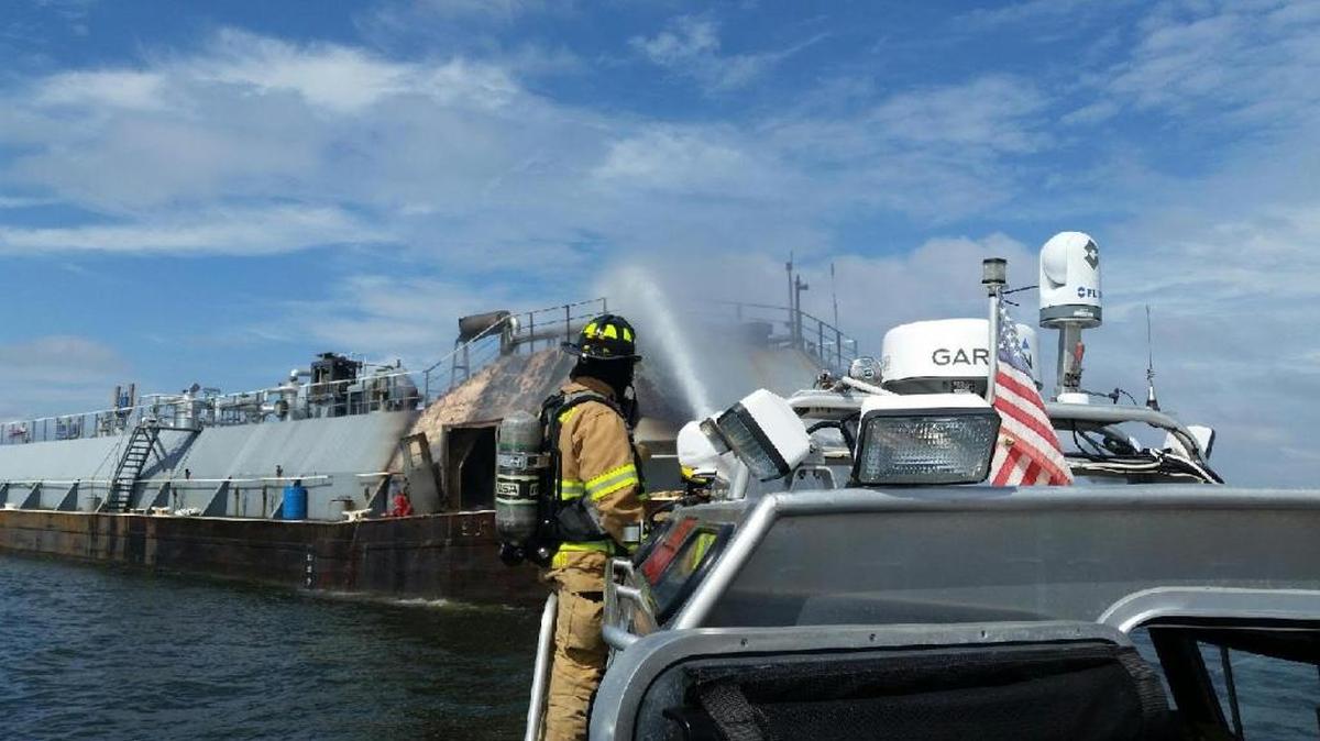 Gulfport fire fighters use a deck hose on their fire boat to put out a blaze on a tug boat in a precarious situation. It was pushing a barge and had anhydrous ammonia and diesel fuel.
