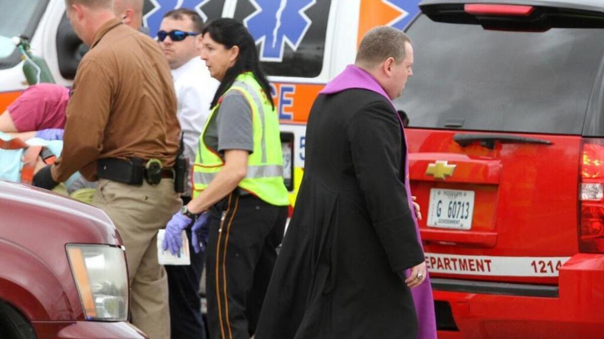 The Rev. Adam Urbaniak with the Catholic Diocese of Biloxi arrives to offer spiritual aid after a charter bus was hit by a CSX train at the Main Street crossing in Biloxi on Tuesday.