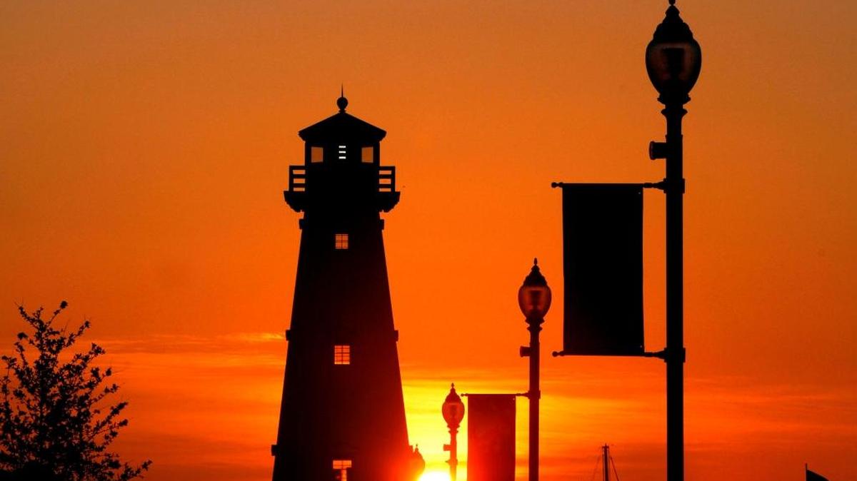 Street lights and the lighthouse are silhouetted against the setting sun at Jones Park in Gulfport.