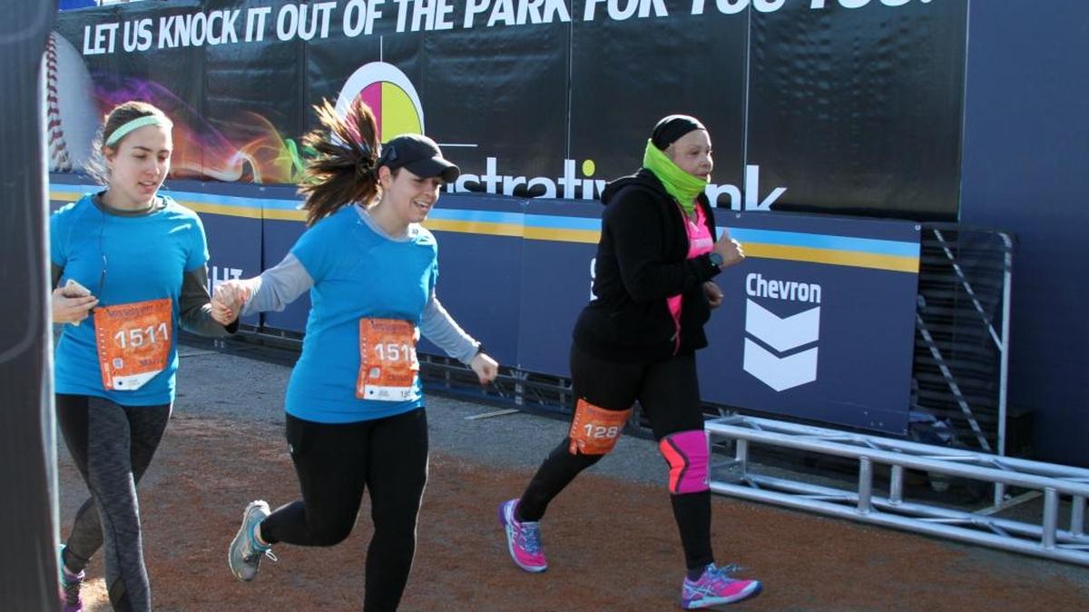 Maria Rodgers, left, of Ocean Springs and sister Christine Rodgers of Pittsburgh, center, finish a half-marathon with their traditional hand-hold, followed by raised arms, along with Sonja McCaskill of Petal.