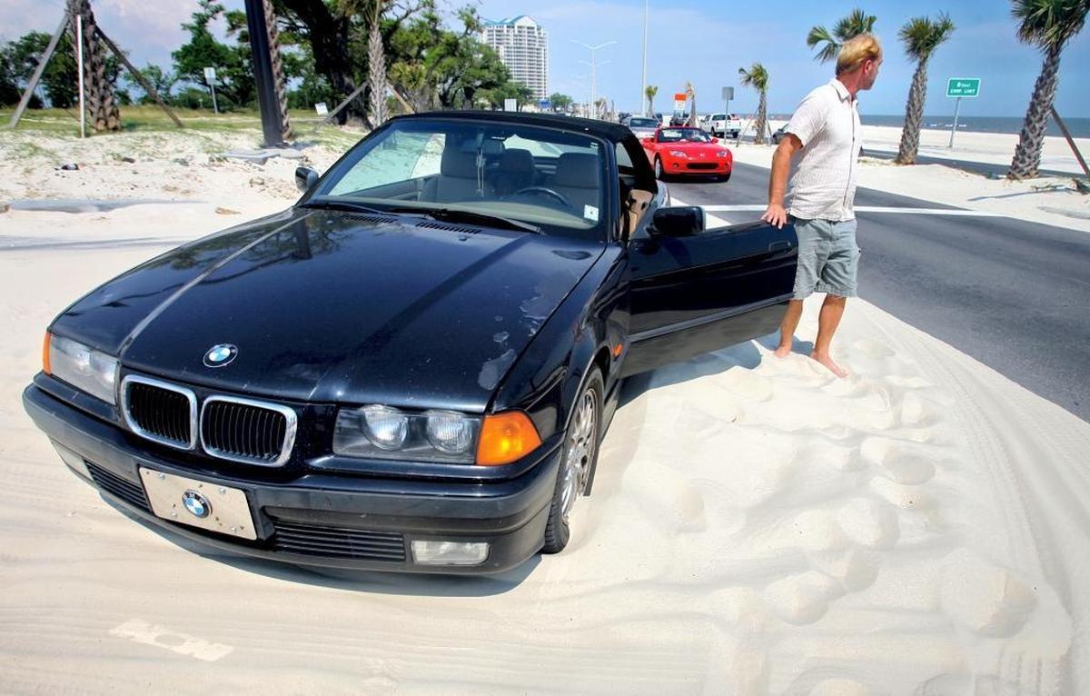 A car gets stuck in deep sand while making the turn onto DeBuys Road from U.S. 90 in Biloxi in May 2009. Sand frequently blows off the beach and onto the highway.