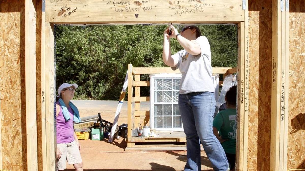 Karen Bruner staples material to a window frame before the window is placed on the future home of Nancy Watling on Monday afternoon. Bruner was participating in the Every Need Project of the First Presbyterian Church of Ocean Springs.