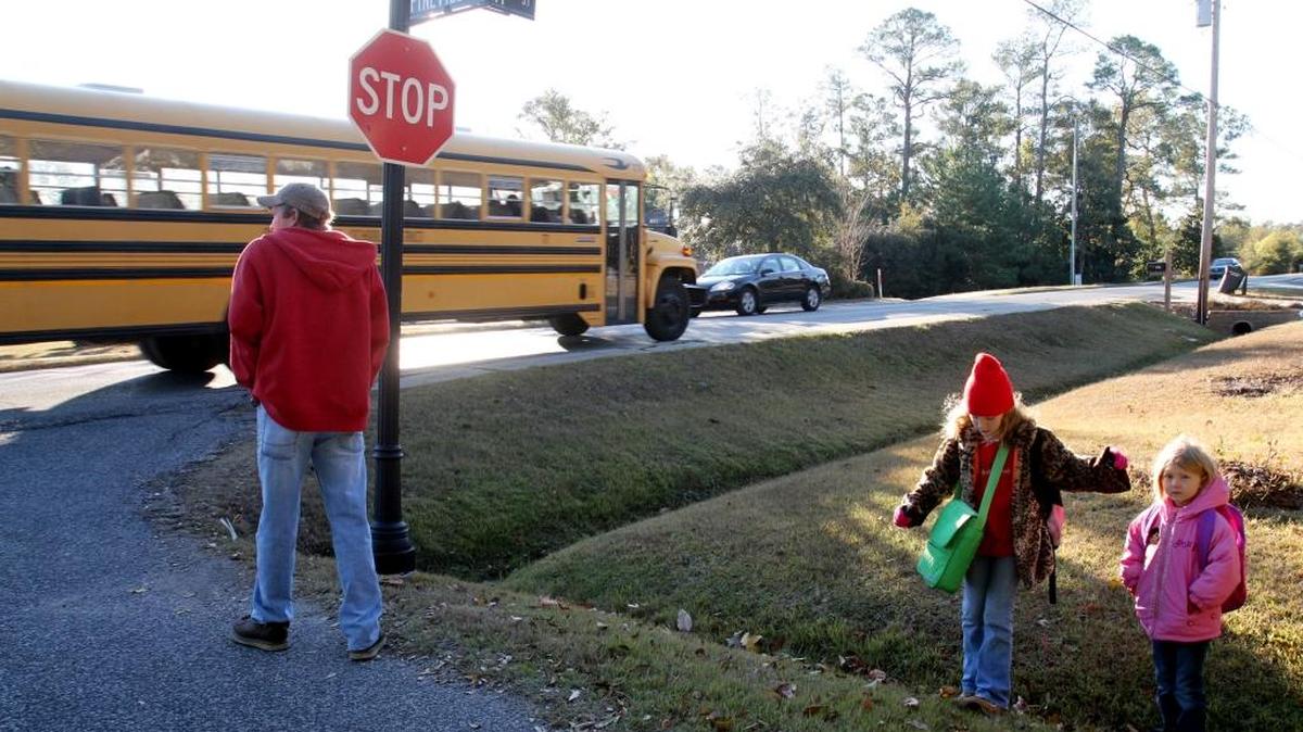 Children wait for an Ocean Springs School district bus in December 2010. The School District announced this week the tax rate will be lower in order to fund school needs in fiscal year 2017.