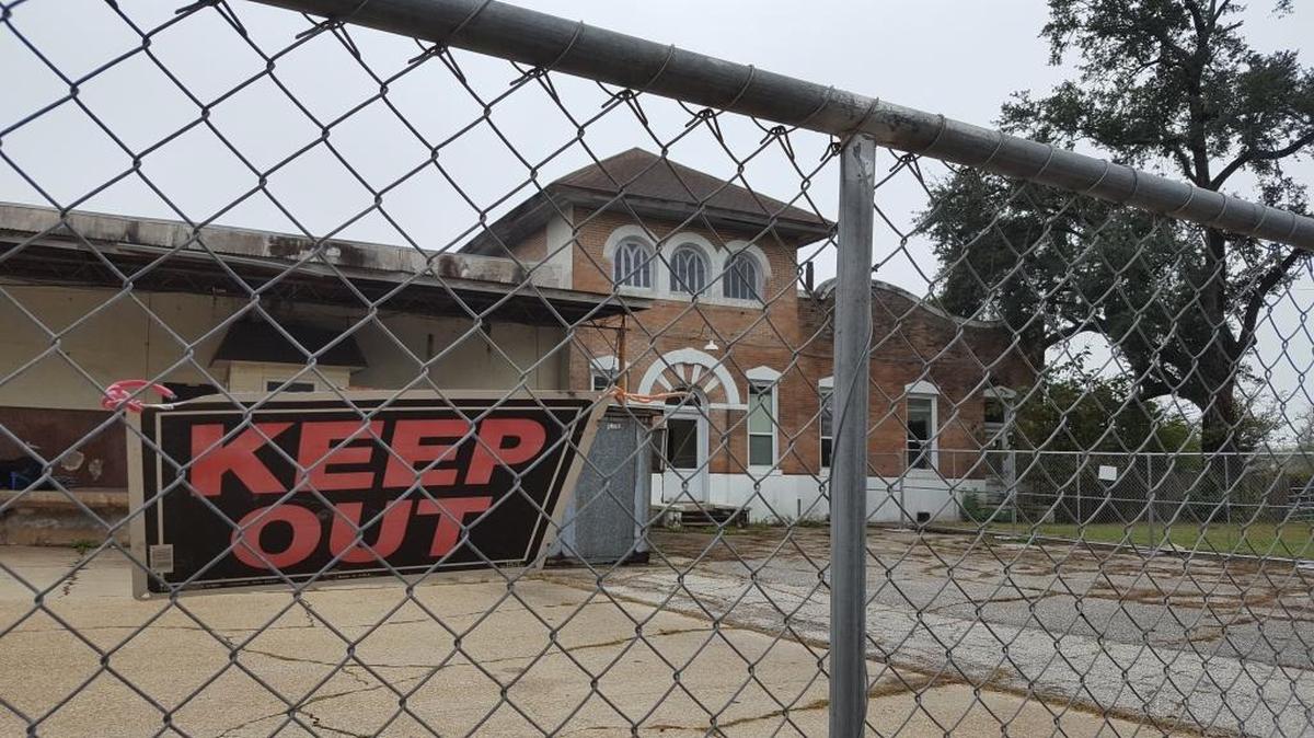 A portion of the historic Pascagoula Ice House is being torn down. The portion with the distinctive architecture, as seen through the fence around the demolition site, will remain and be sold as part of the three acres near U.S. 90.