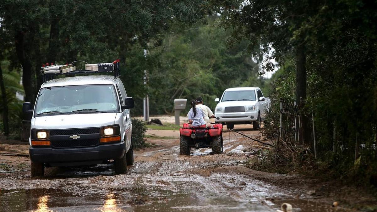 Vehicles carefully pass through a section of Belle Fountain Drive south of St. Andrews Golf Course that was washed out following Hurricane Nate's aftermath on Sunday, October 8, 2017.