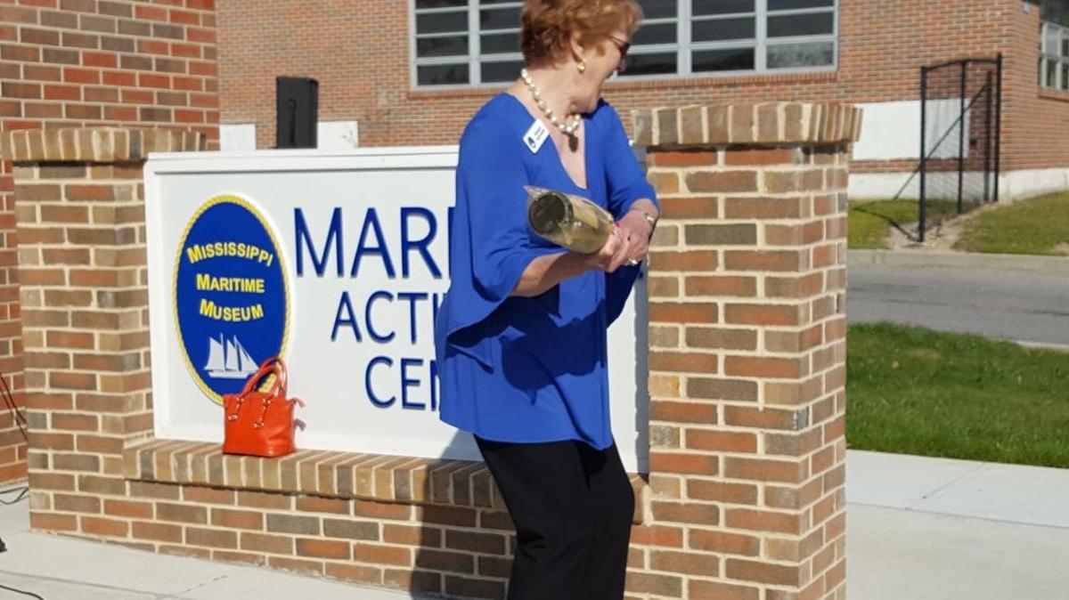 Peggy Hoover, wife of the founding father of the Mississippi Maritime Museum, christens the entrance to the museum’s new activity center on Thursday. Project completion date for the museum is 2020.