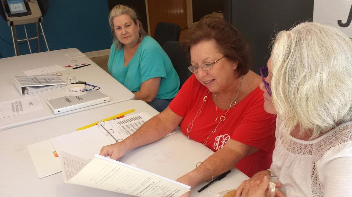 Hannah Moran, Tammy Baker and Jackie McAdams, from left, check the poll books at Oasis Church on Pascagoula Street polling place. About 35 people had voted at that precinct by 10 a.m.
