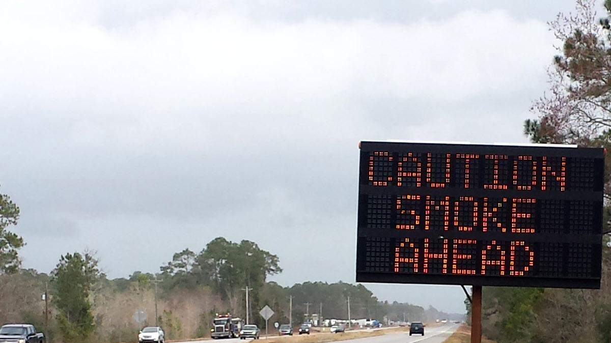 A portable sign warns motorists of smoke from the Grand Bature fire in Jackson County possibly affecting visibility on U.S. 90.