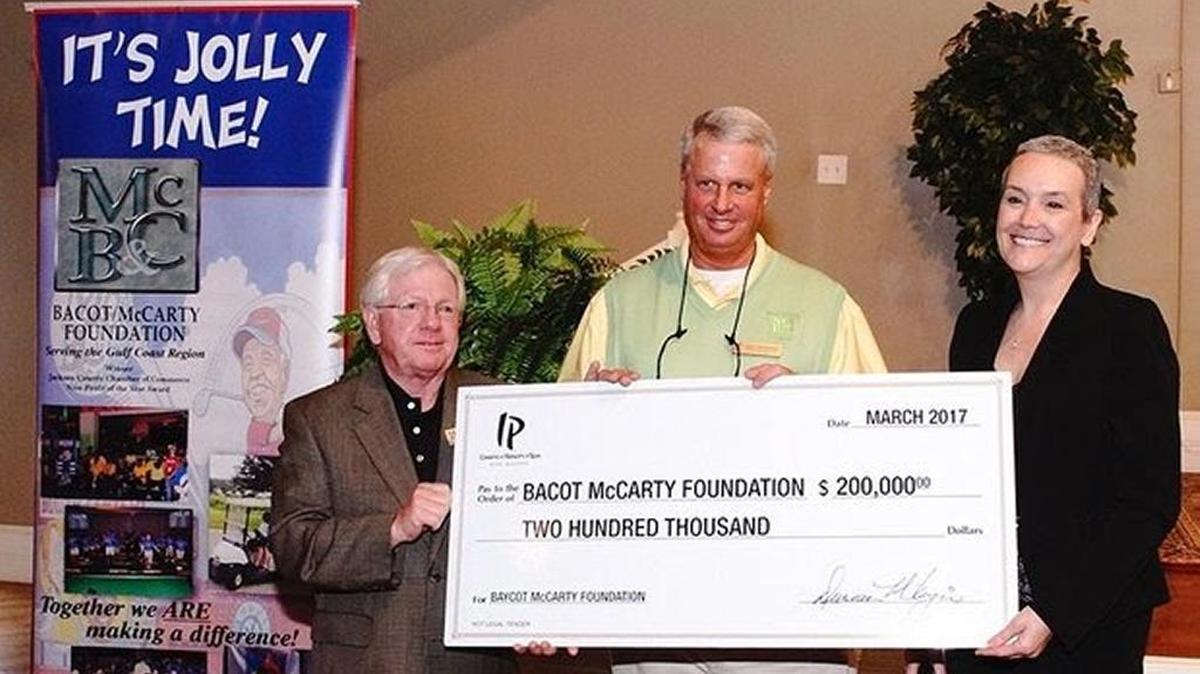 Rich Westfall, left, board chairman of the Bacot-McCarty Foundation, and Todd Trenchard, foundation executive director, center, accept a $200,000 donation from IP Casino Resort Marketing Director Kim Goetz during the March 24 Jolly McCarty Memorial Weekend kickoff breakfast in Pascagoula.