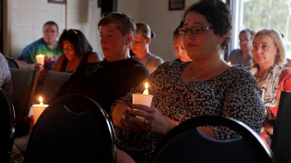 Georgia Harris joins a group as they light candles during vigil in memory of Dee Whigham at Lighthouse Community Church in Biloxi, Wednesday night.