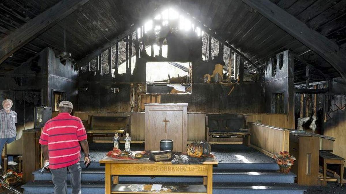 Bayou Baptist Church members Milton Deal, left, and Clarence Powe look over the damage to the sanctuary after an arson Oct. 13, 2015.