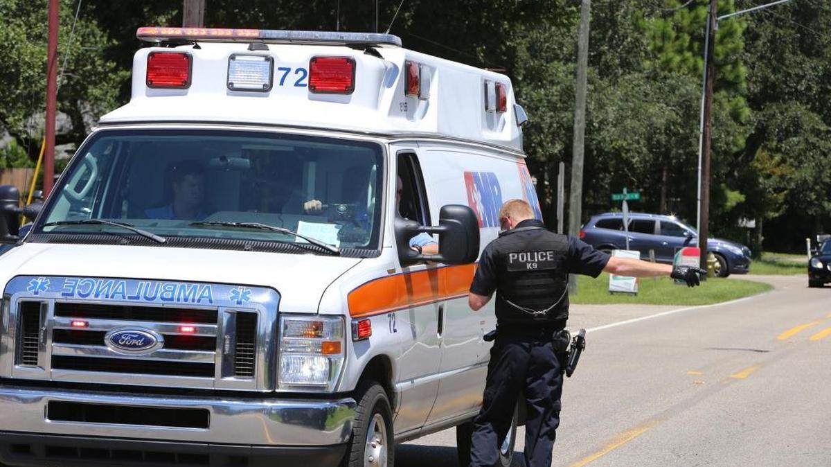 A Long Beach police officer directs an the driver of an AMR ambulance arriving at the scene of an armed robbery at Long Beach in 2017. Cities across the state are reviewing their contracts with AMR in an effort to improve response times.
