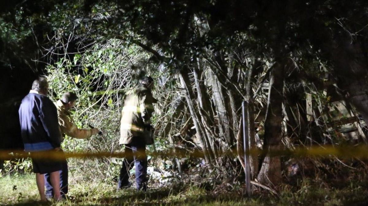 D'Iberville police officers and firefighters work Sunday, Jan. 22, 2017, to retrieve a body from a metal shed behind a vacant house off Lemoyne Boulevard.