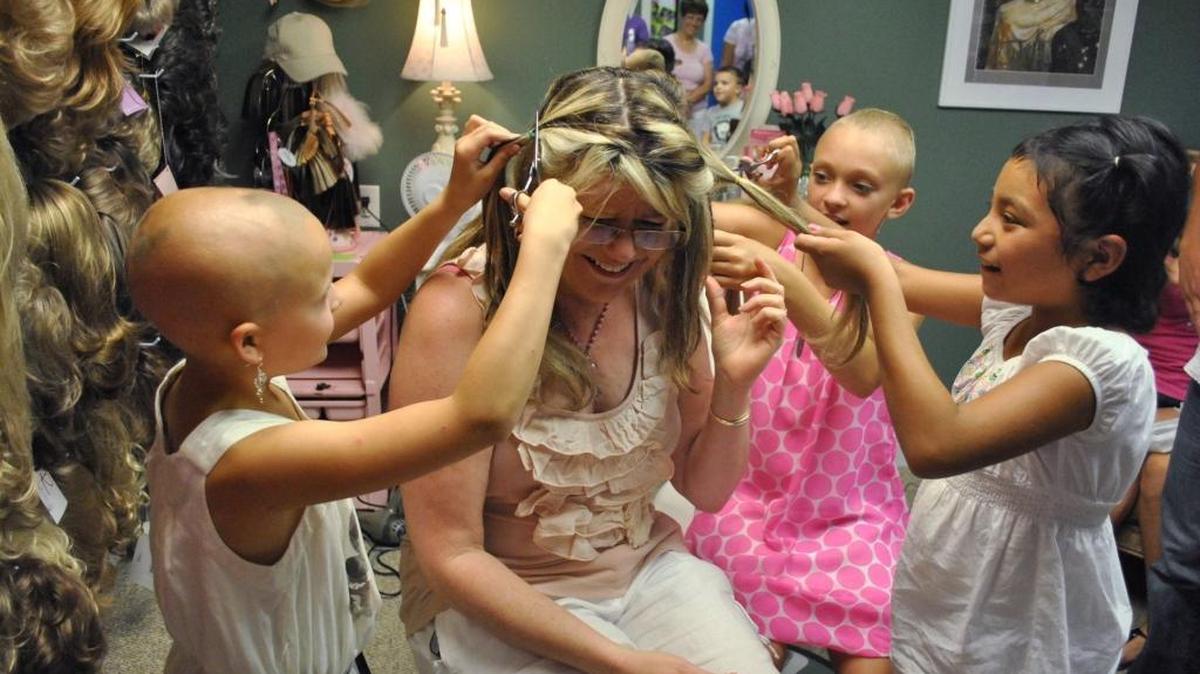 Whitney Barnhardt, 9 of Lumberton, Mary Michael Sullivan, 11 of Gulfport, and Abigail Ramirez, 8 of Pass Christian cut pigtails off of Pink Heart Funds founder JoAn Niceley in 2011.