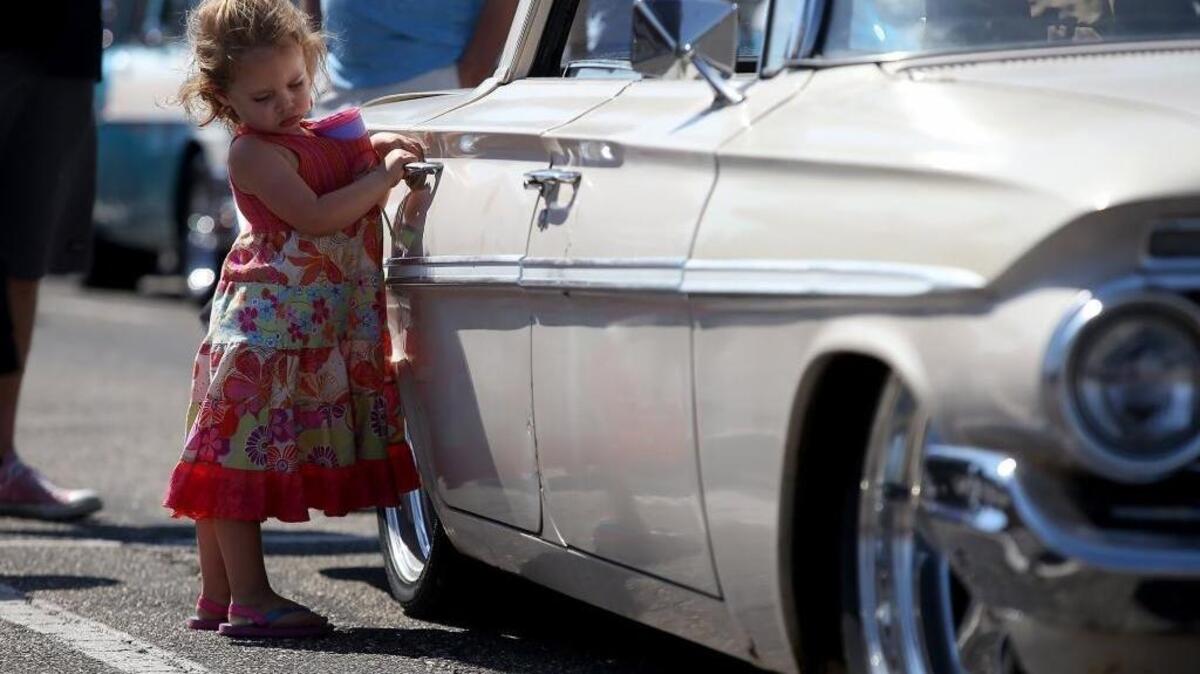 Rose Martin, 3, plays with the door handle of a 1961 Chevrolet Belair during Cruisin' The Coast on Saturday, October 8, 2016, at the Edgewater Mall.