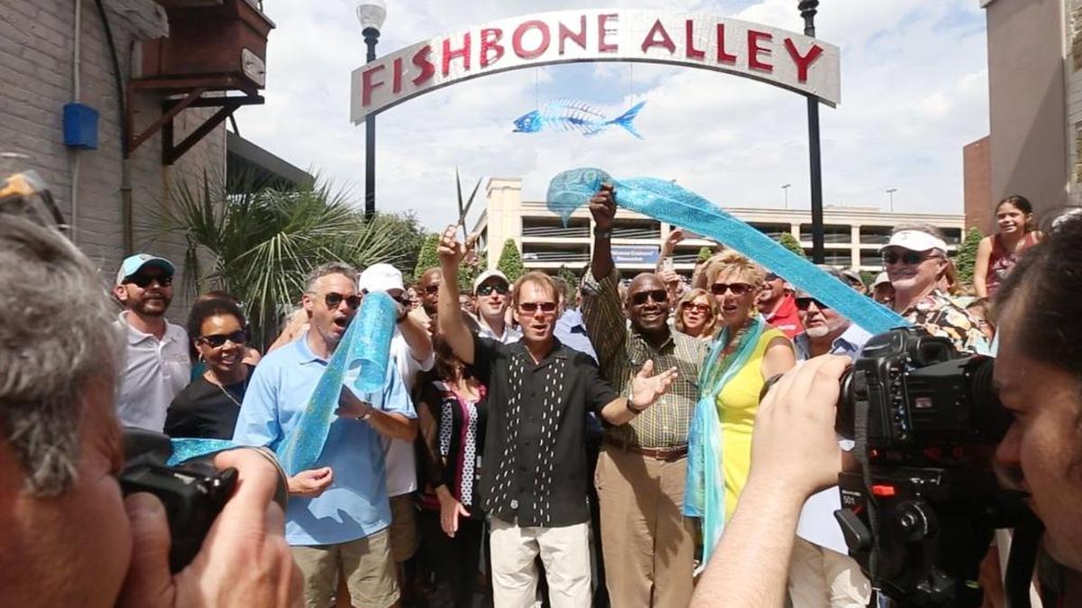 Gulfport Mayor Billy Hewes, center, and other city officials cheer after cutting the ribbon on Fishbone Alley in downtown Gulfport, Sunday, Oct. 3, 2016.