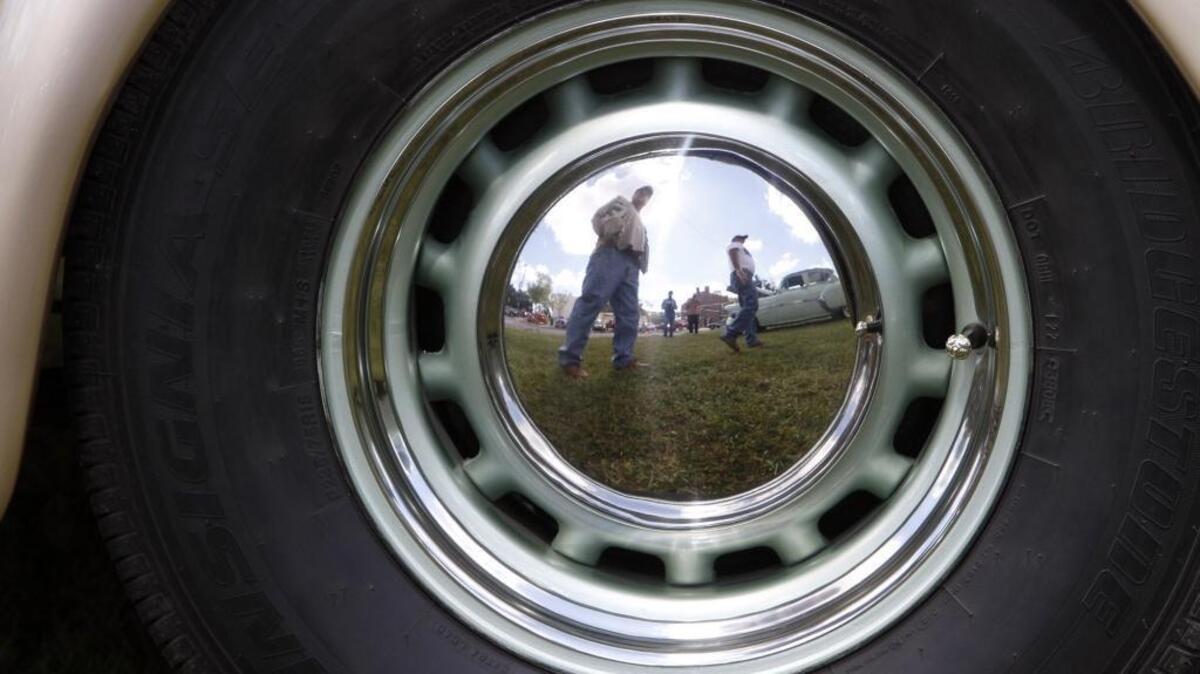 Jim Kelly and Luke King of Pine Mountain, Ga., are reflected in the hubcap of a Studebaker as Cruisin' the Coast makes a stop in Moss Point, Tuesday morning.