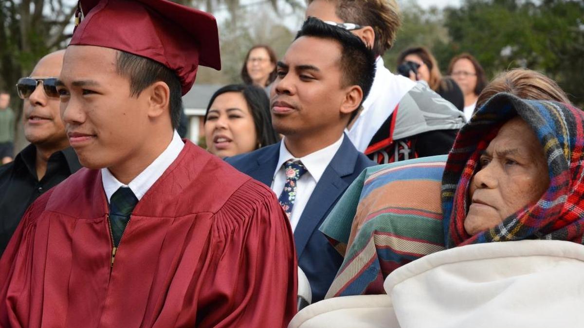 Noah La’Cap, left, and his father, Alfred La’Cap, who was diagnosed with cancer last year, listen to Long Beach High School Principal Larry Ramsey give graduation remarks Friday.