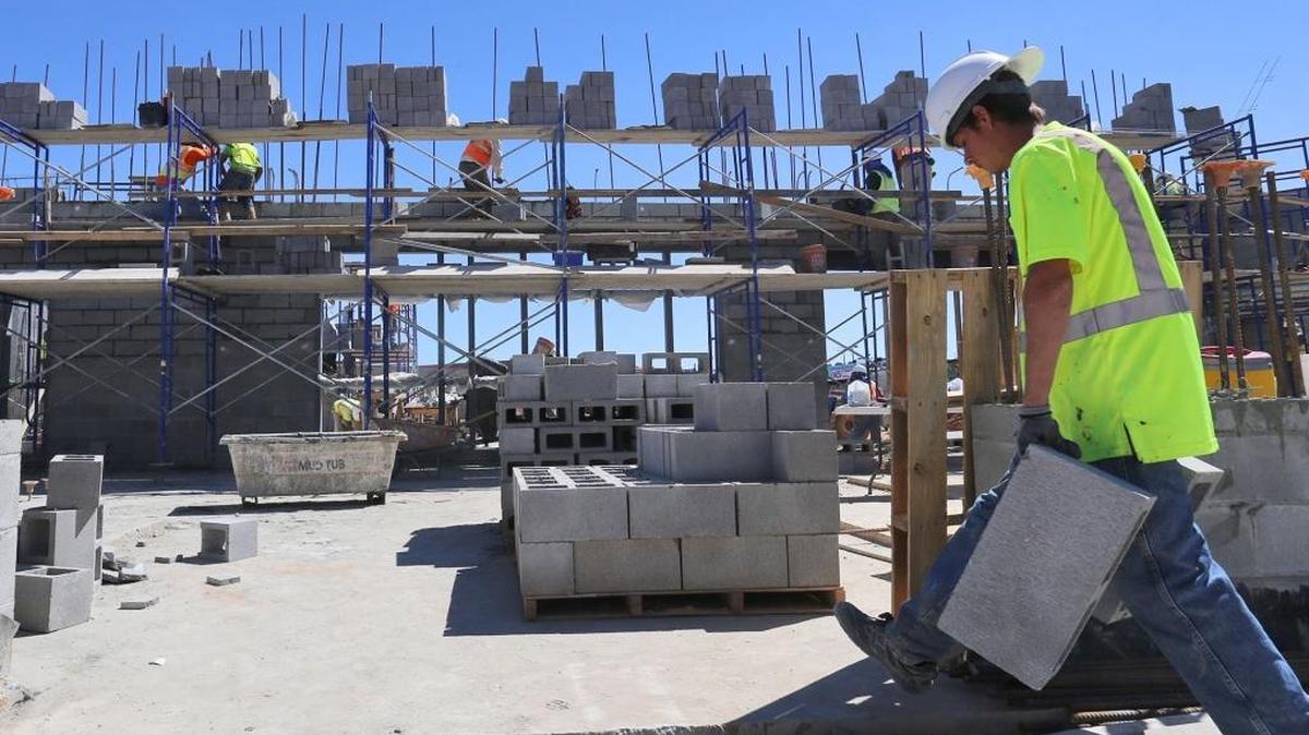 A worker carries blocks to masons as they build the new Biloxi Junior High School campus Friday, Sept. 30, 2016.