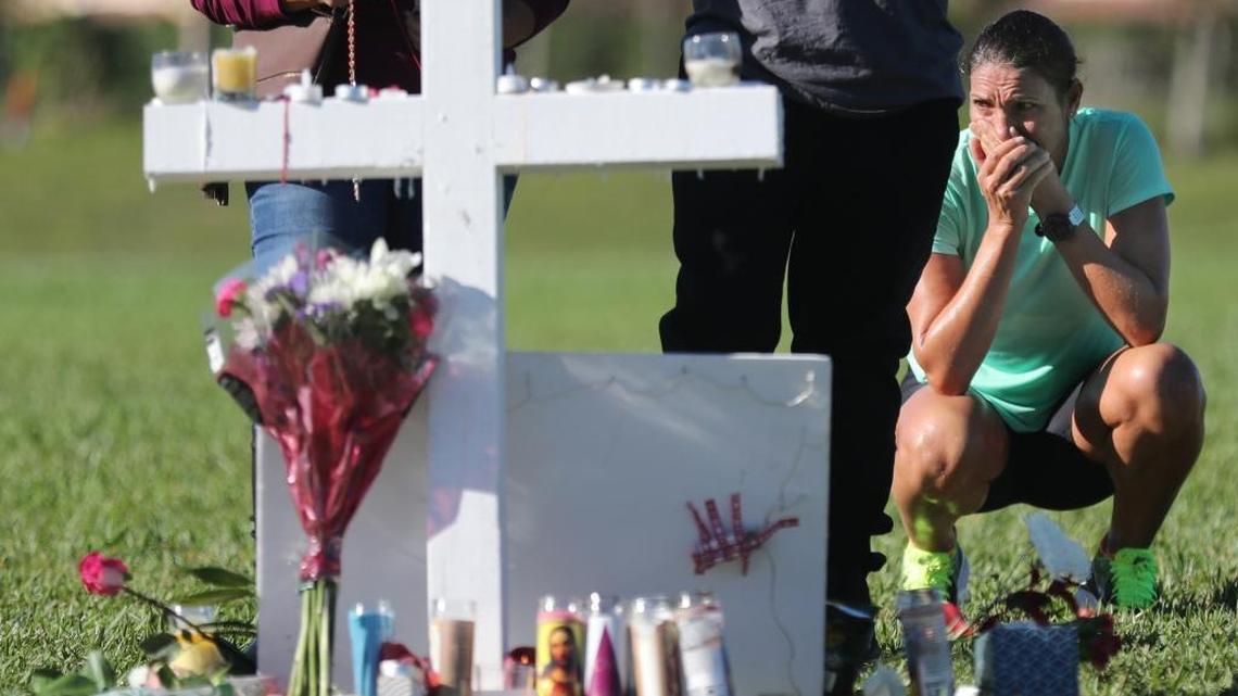Maria Creed is overcome with emotion as she crouches in front of one of the memorial crosses at Pine Trails Park in Parkland, Florida, on Friday, Feb. 16, 2018. White crosses stand in a field at the park to memorialize the 17 people killed Wednesday at Marjory Stoneman Douglas High School. Creed's son, Michael Creed, is a sophomore at the school.
