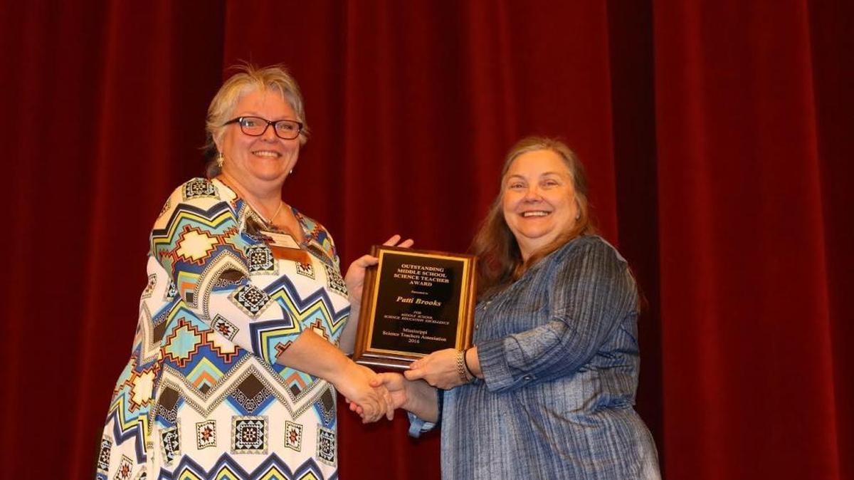 Patti Brooks, left, of D’Iberville Middle School receives the Outstanding Middle School Teacher from Kelle Sumrall, district director and co-director of publicity for the Mississippi Science Teachers Association.