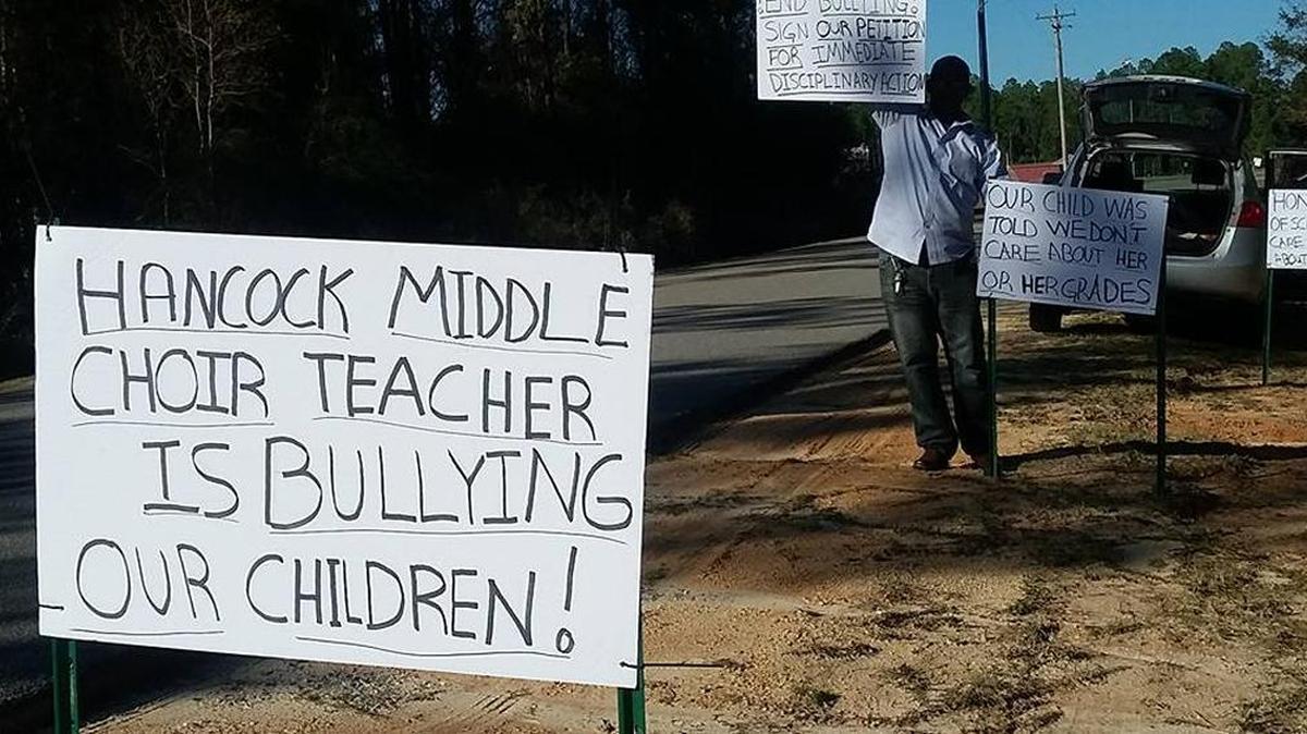 A Hancock Middle School parent holds a picket sign in front of the school on Friday, Dec. 9, 2016.