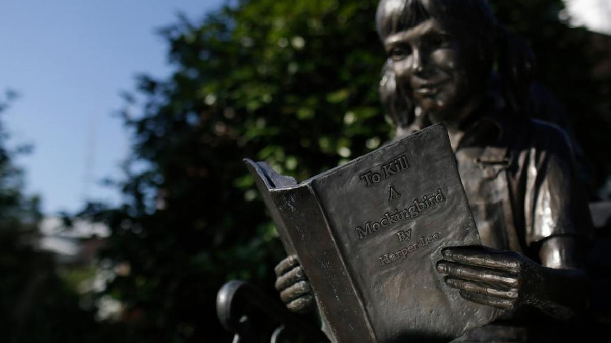 A young girl statue reads ‘To Kill a Mockingbird’ by author Harper Lee on July 13, 2015, in Monroeville, Ala. The American classic was pulled from the eighth-grade lesson plan at Biloxi schools after a complaint from a parent about the students’ response to the book’s use of racial language.