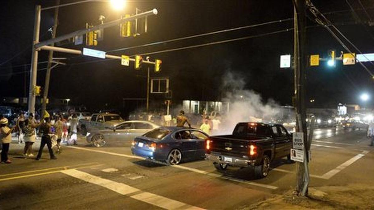 Protestors gather at the intersection of N. Foster and Fairfields, Tuesday, near the Triple S Food Mart after Alton Sterling was shot and killed by Baton Rouge Police in the early hours of Tuesday morning, July 5, 2016, in Baton Rouge, La. An autopsy shows Sterling, 37, of Baton Rouge, died Tuesday of multiple gunshot wounds to the chest and back, said East Baton Rouge Parish Coroner Dr. William Clark. Officers responded to the store about 12:35 a.m. Tuesday after an anonymous caller indicated a man selling music CDs and wearing a red shirt threatened him with a gun, said Cpl. L'Jean McKneely. (Hilary Scheinuk/The Advocate via AP)