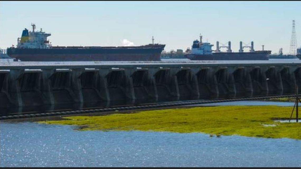Ships at anchor in the Mississippi River near the Bonnet Carre Spillway as water trickles down on the road below.