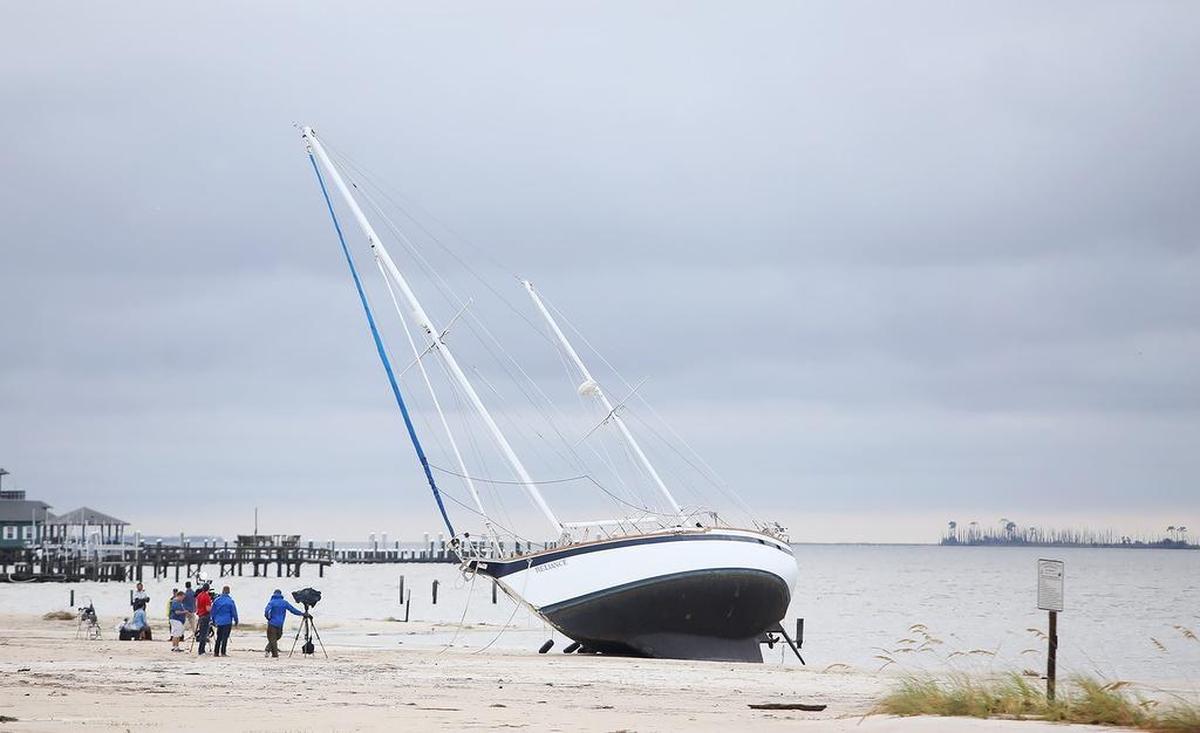 Television crews surround a boat that washed ashore on the beach in Biloxi sometime during the night as Hurricane Nate made landfall.