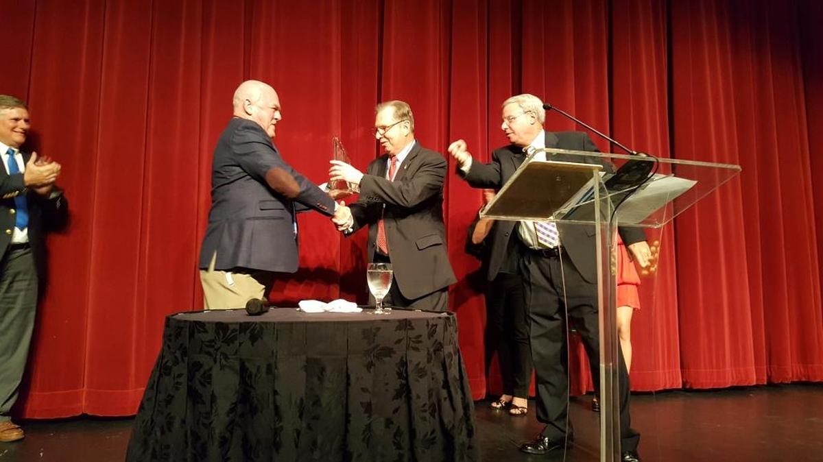 Steve Miner presents the Blossman YMCA Humanitarian Award to Mickey Williams as emcee Todd Trenchard looks on.