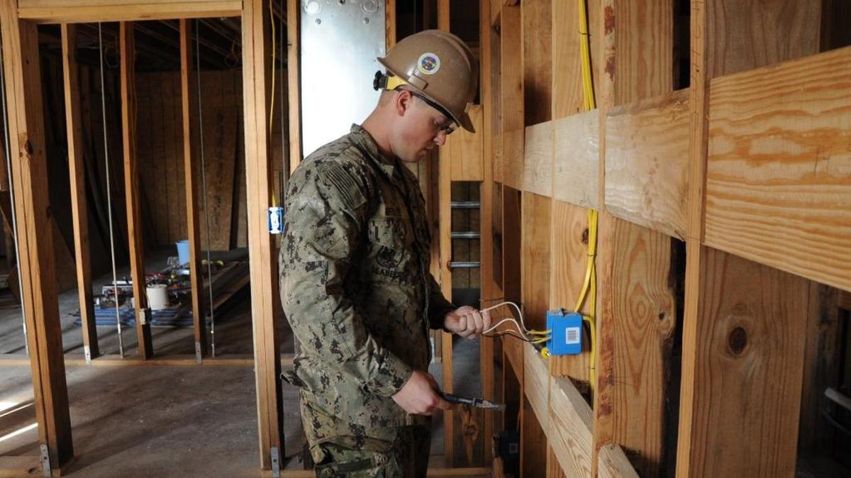 Construction Electrician 3rd Class Tyler Benvie, from Porter, Maine, runs electrical wire at the Wiggins Irregular Training Project, in Wiggins, Mississippi, on March 13, 2018. NMCB 1 is a Seabee Battalion specializing in contingency construction, disaster response, humanitarian assistance and combat operations support.