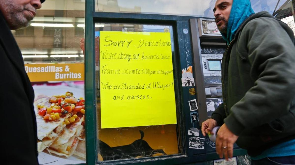 Zamood Zokari, left, and Ali Elazab, right, post a sign on a window of Zokari' family deli in lower Manhattan, alerting customers that the store will close because of a protest against President Donald Trump's travel ban, Thursday, Feb. 2, 2017, in New York. Yemeni business owners who operate corner bodegas and neighborhood delis shut them down on Thursday in protest of the travel ban on people hailing from seven Muslim-majority countries including Yemen.