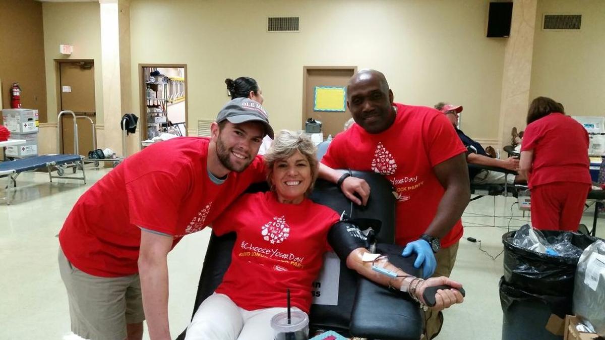 Blood donor Jen Myers, center, is supported by her son, cancer survivor Nick Myers, and Red Cross staff member G. West at a recent blood drive in Gulfport’s Orange Grove community.