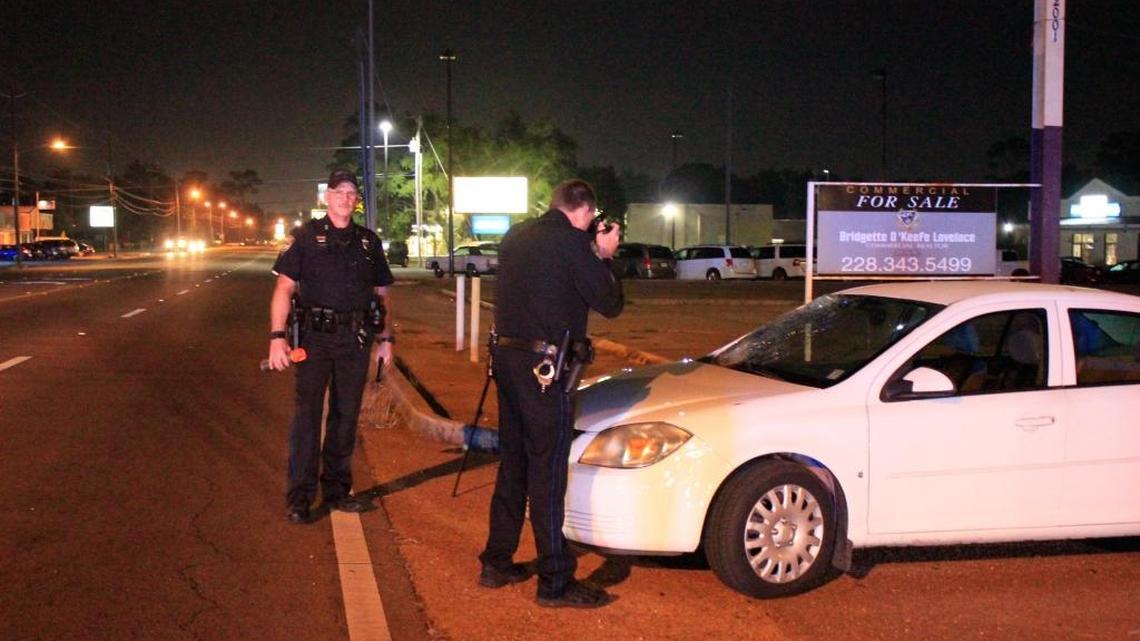 Gulfport police officers photograph a Chevy Cobalt that hit and killed a pedestrian on Pass Road on Monday night.
