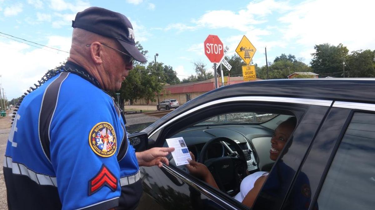 Biloxi Police Patrolman First Class Scott Saucier hands out fliers about railroad crossing safety from Mississippi Operation Lifesaver on Tuesday at the Nixon Street crossing in Biloxi. This crossing is just east of where a tour bus that was stuck on the crossing was hit by a train and four people died.