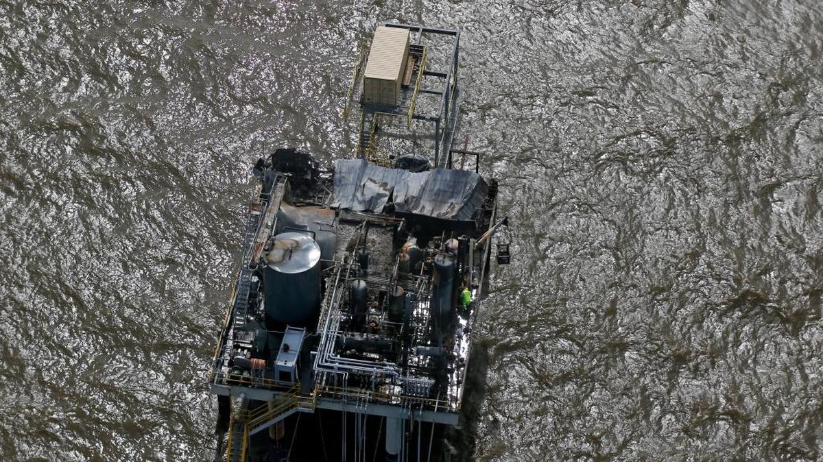 A worker stands on an oil and gas platform in Lake Pontchartrain in Kenner, La., that exploded overnight near New Orleans, Monday, Oct. 16, 2017. Seven people were injured, including three who were in critical condition, authorities said. Authorities searched by air and water Monday for a contractor who disappeared in the blast.