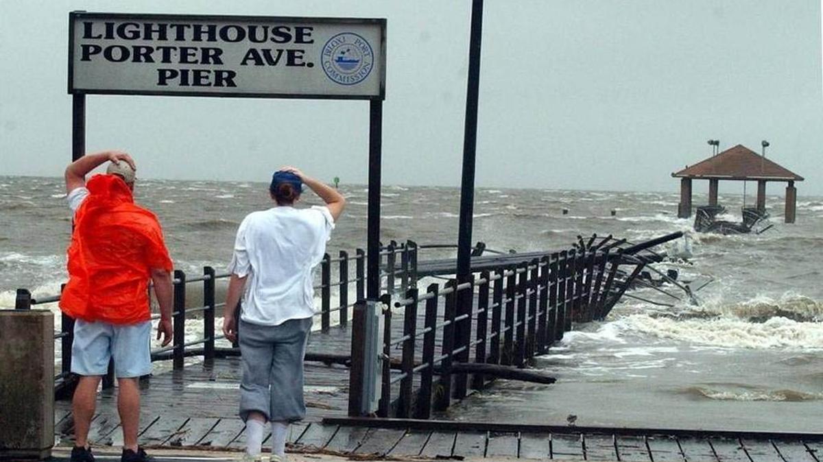 Jim Swango, left, and his step-daughter Holly Fuller look at the damage to the Lighthouse-Porter Avenue Pier in Biloxi in September 2002 as the storm surge from Tropical Storm Isidore washes over it.