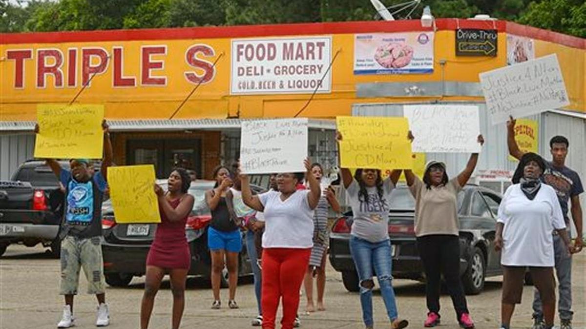Family and friends of Alton Sterling protest on the corner of Fairfields Ave. and North Foster Drive Tuesday afternoon, July 5, 2016, after was fatally shot in an altercation with Baton Rouge Police just after midnight, in the parking lot of the Triple S Food Store, in Baton Rouge, La. They chanted things including "Hands up, don't shoot!" Officers responded to the store about 12:35 a.m. Tuesday after an anonymous caller indicated a man selling music CDs and wearing a red shirt threatened him with a gun, said Cpl. L'Jean McKneely. (Travis Spradling/The Advocate via AP)